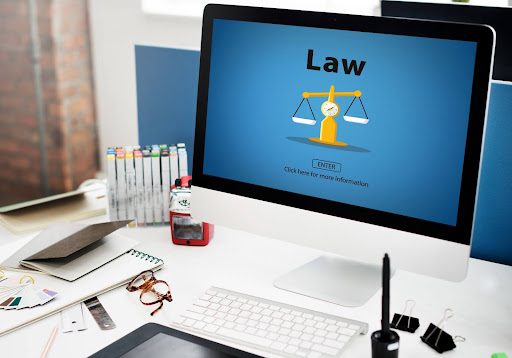 Interactive website development interface with justice scale icon on a computer monitor, symbolizing online presence for law firms