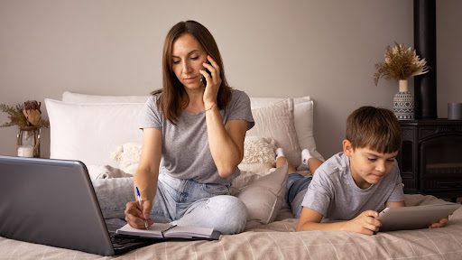 Busy mother managing family law matters online while child plays, depicting the convenience of accessible family law websites.