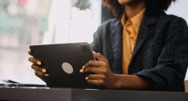 Woman holding a tablet while sitting at a desk