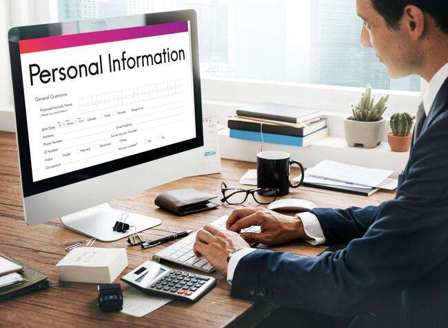 Man working on a computer with a form titled "Personal Information" displayed on the screen.